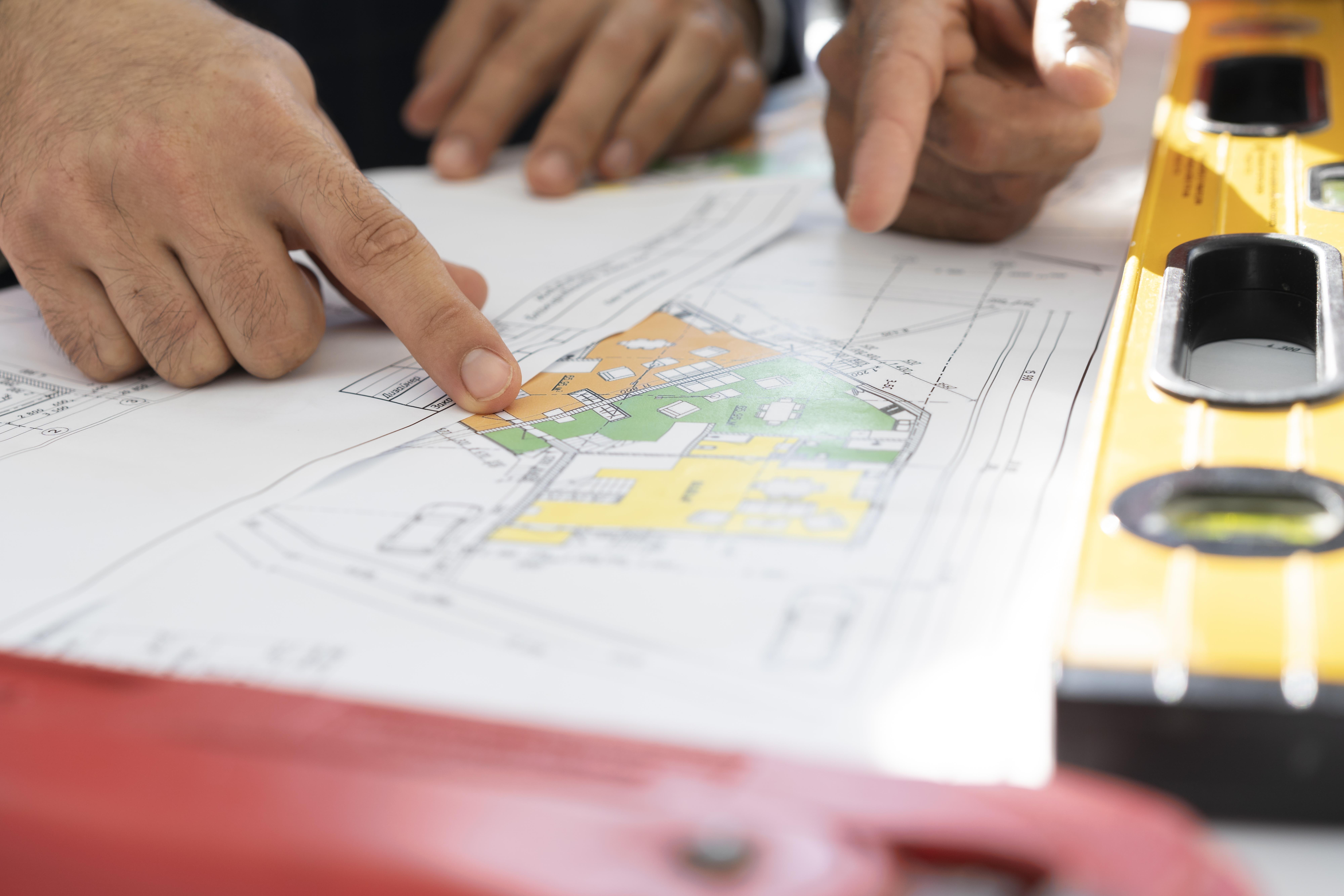 une carte d'urbanisme est dépliée et montrée du doigt